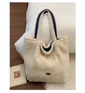 Dettaglio della borsa tote in pile crema con manici in tessuto blu navy e stemma