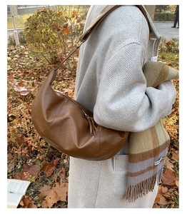 Macro shot of brown leather dumpling bag with decorative tassel and adjustable strap