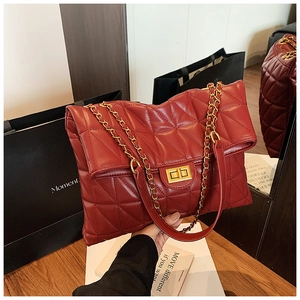 Détail du sac cabas en cuir matelassé rouge avec chaîne dorée et fermoir pivotant