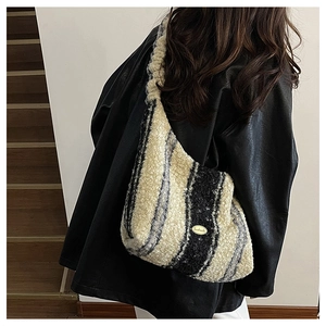 Detail of handmade metal tag on striped plush faux fur shoulder bag for winter fashion