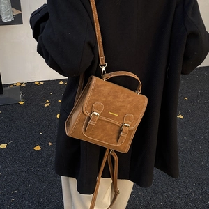 Brown vintage faux suede backpack on a shoulder with autumn ginkgo leaves background