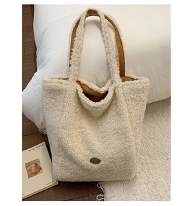 Dettaglio borsa a secchiello in peluche bianca con manico in camoscio e targa Handmade