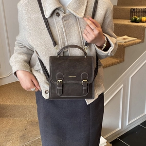Vintage dark brown leather backpack with buckle detail and top handle on stairs