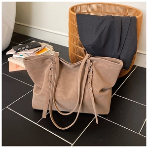 Detail of coffee brown tote bag with metal eyelet straps on minimalist background