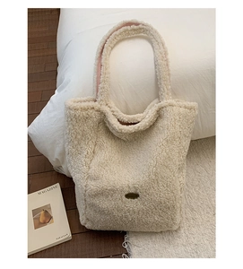 Dettaglio borsa tote in pelliccia sintetica bianco sporco con tracolla rosa e placca