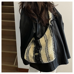 Detail of plush zebra stripe hobo bag with knotted strap and metal logo on a model
