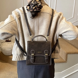 Detail of dark brown vintage backpack featuring metallic buckles and textured leather