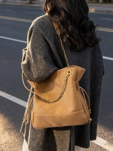Quilted camel leather tote bag with gold chain strap shown on a model in sunlight