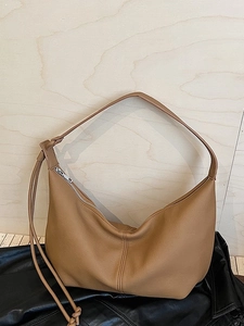 Brown leather hobo bag with pebble texture and silver zipper on a wooden surface