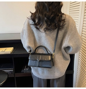 Rear view of a model styling a black faux leather crossbody bag with gold hardware detail