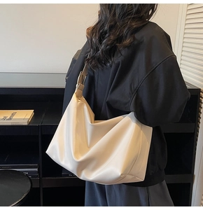 Detail of a large creamy white faux leather tote bag showing soft texture and strap buckle