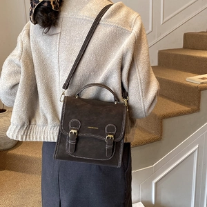 Detail of dark brown vintage backpack featuring matte leather texture and gold buckles