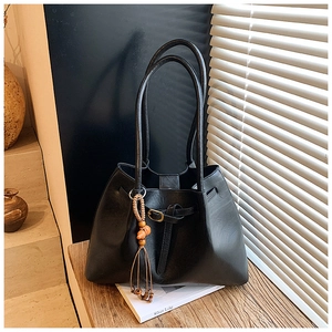 Détail du sac cabas en cuir noir avec breloque ethnique et pompon au style bohème chic