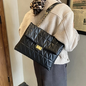 Détails d'un sac matelassé noir avec chaîne dorée et fermoir pivotant carré élégant