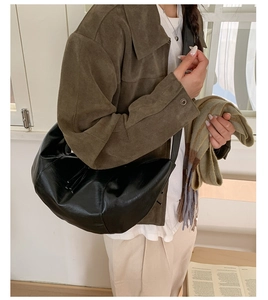 Dettaglio di una grande borsa hobo in pelle PU nera con trama a pieghe sulla modella