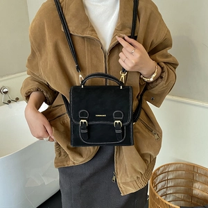 Close-up of vintage black matte shoulder bag with golden buckles and fashion lettering