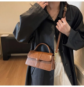 Detail showing high-quality dark brown leather texture and gold hardware of the square handbag