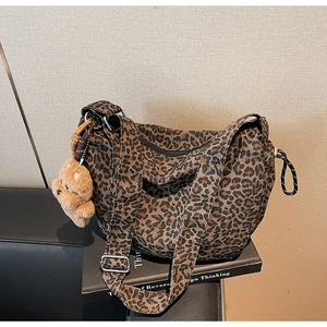 Gros plan du sac en toile léopard avec bandoulière large et breloque ours en peluche