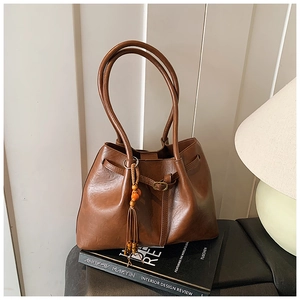Gros plan d'un sac cabas marron en cuir avec pompon élégant et anneau métallique