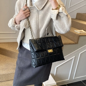 Détail du sac bandoulière matelassé noir avec chaîne dorée et fermoir métallique carré