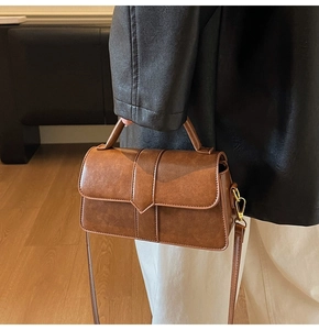 Brown vintage leather handbag with adjustable strap shown against a chic fashion outfit
