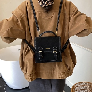 Detail of black mini backpack with white contrast stitching and gold buckle hardware