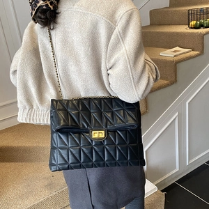 Vue détaillée du grand sac matelassé noir avec fermoir doré porté par un mannequin