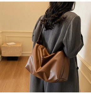 Detailed back view of a retro brown leather tote bag worn on shoulder by a model