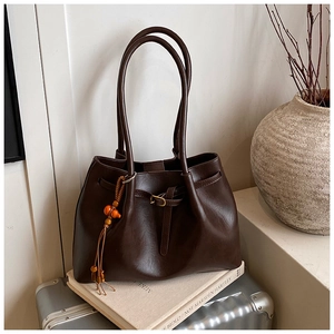 Gros plan d'un cabas vintage marron avec boucle en métal et breloque à pompon