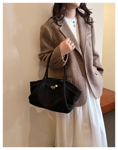 Detail of black suede tote bag with golden metal buckle clasp and soft leather texture