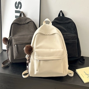 Detailed view of vintage PU leather backpacks in brown, white and black with plush charms