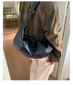 Detail view of large black crescent moon bag in soft leather with adjustable strap