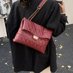 Gros plan d'un sac à bandoulière matelassé rouge vin avec chaîne et fermoir doré