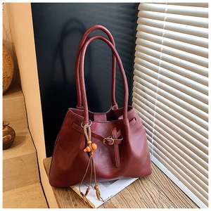 Détail du sac cabas vintage bordeaux avec cordon, pompon en perles de bois et lumière