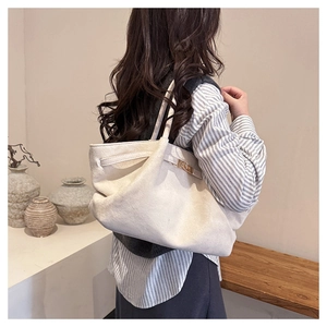 Detail of white suede tote bag featuring a golden metal twist lock and minimalist strap