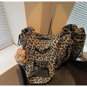 Détail du sac cabas léopard montrant la bandoulière large et le charm d'ourson