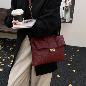 Détail du sac bandoulière matelassé bordeaux avec fermoir doré et bandoulière chaîne
