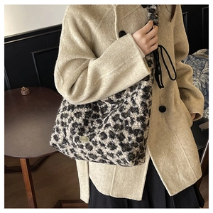 Macro shot of fluffy leopard print plush tote bag with metallic oval logo detail