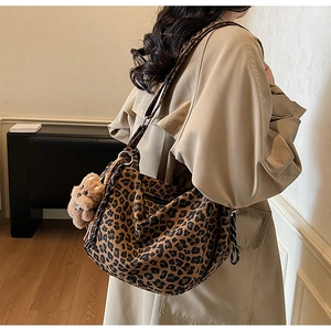 Detail of leopard print hobo bag with woven strap and brown plush bear charm accessory