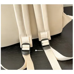 Detailed close-up of cream synthetic leather backpack with adjustable woven shoulder straps