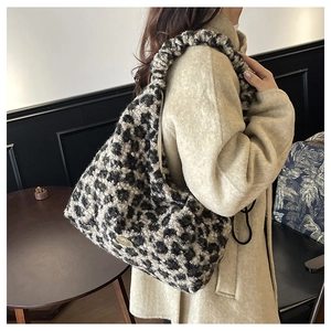 Detail of plush leopard print faux fur tote bag with a golden metal brand plate