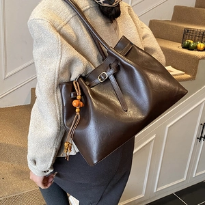 Détail du grand sac cabas en cuir marron avec pompon en bois et boucle élégante