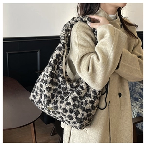 Detail of leopard print plush tote bag showing soft texture and metal logo plaque