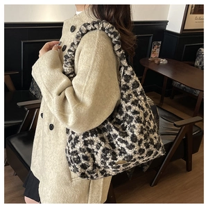 Detailed view of the leopard print texture and round metal logo on a plush shoulder bag