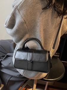 Chic black leather handbag with crossbody strap shown on model in cozy winter outfit