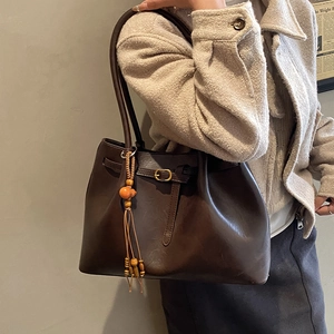 Détail d'un sac cabas en cuir marron vintage avec pampilles et boucles métalliques