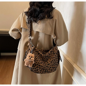 Sac fourre-tout léopard avec breloque ours en peluche porté sur un trench-coat kaki