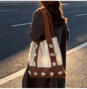 Detail of knitted tote bag with 3D floral accents in cream and caramel brown colors