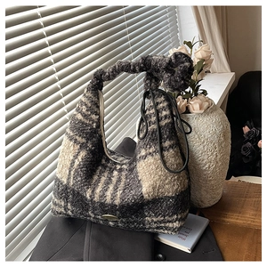 Detail of plaid faux shearling tote bag with knotted handle and metal logo on blazer