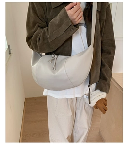 Dettaglio di borsa beige a mezzaluna con nappa sulla cerniera e finitura in ecopelle